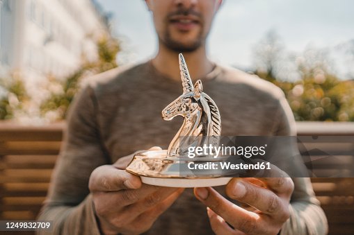 Young entrepreneur holding unicorn figurine, close up Young entrepreneur holding unicorn figurine, close up