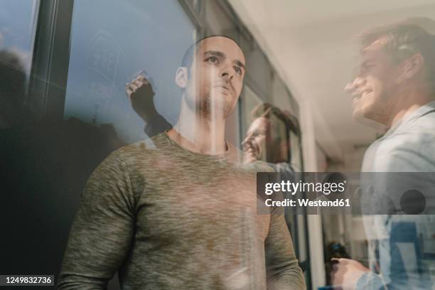 young pensive man leaning on wall during a business meeting - mitteleuropa stock-fotos und bilder