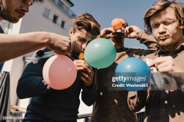 group of friends playing with balloons ona balcony - inflate stock-fotos und bilder