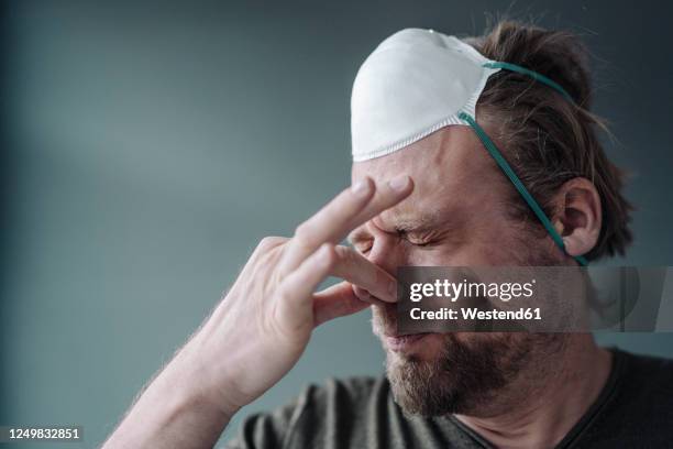 portrait of man with protective mask holding nose - fetid stock pictures, royalty-free photos & images