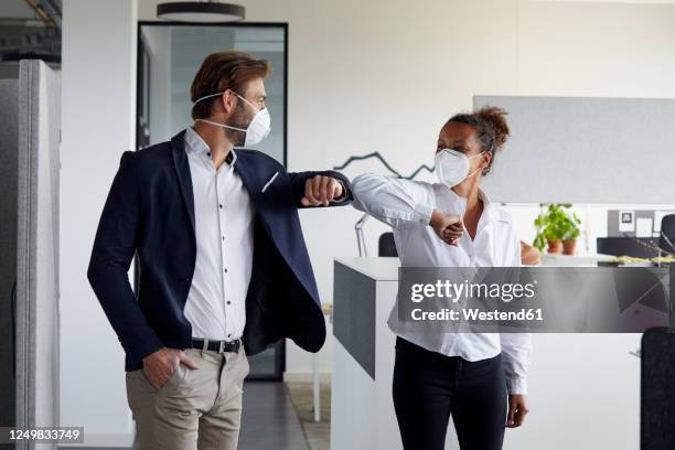 colleagues greeting each other in office during corona crisis - covid greeting stock pictures, royalty-free photos & images