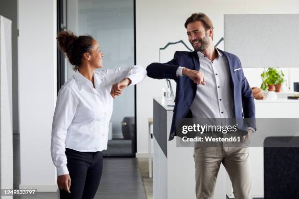 colleagues greeting each other in office during corona crisis - elbow stockfoto's en -beelden