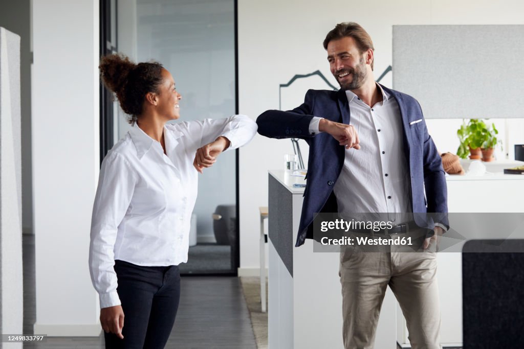 Colleagues greeting each other in office during Corona crisis