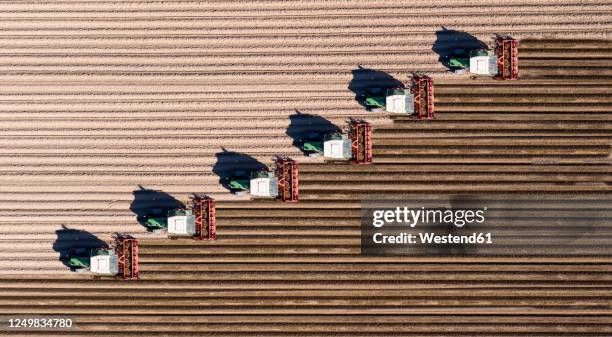 germany, hesse, bergstarsse, aerial view of tractors plowing brown field in spring - cultivated land fotografías e imágenes de stock