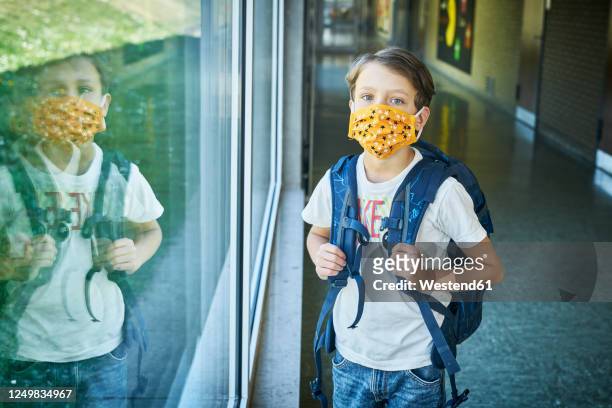 boy wearing mask in school mirrored in window - surgical mask stock-fotos und bilder