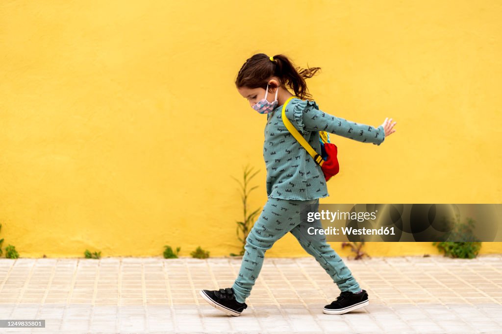 Girl walking with backpack and mask outdoors