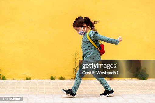 Girl walking with backpack and mask outdoors Girl walking with backpack and mask outdoors