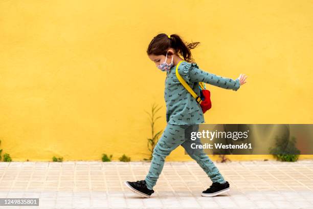 girl walking with backpack and mask outdoors - protective face mask side stock pictures, royalty-free photos & images