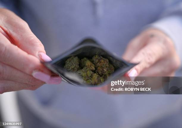 Customer displays a bag of "flower", or marijuana bud, that she purchased at an unlicensed cannabis dispensary in unincorporated Los Angeles County,...