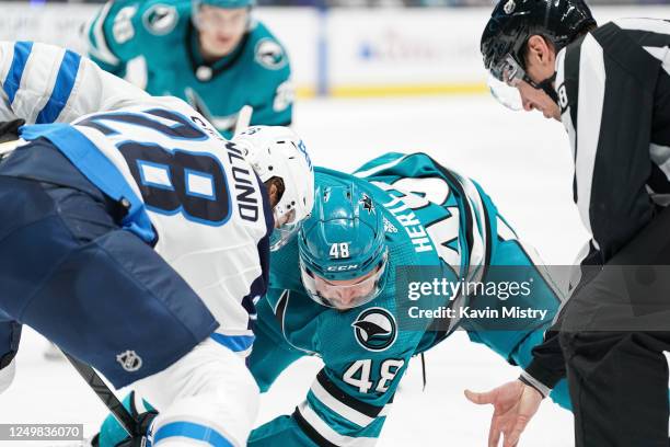 Tomas Hertl of the San Jose Sharks takes a face-off in the third period against Kevin Stenlund of the Winnipeg Jets at SAP Center on March 28, 2023...