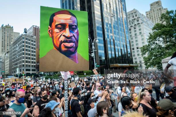 Hundreds of people pack into Columbus Circle to hear speeches against police violence while one of them holds a painted portrait of George Floyd in...