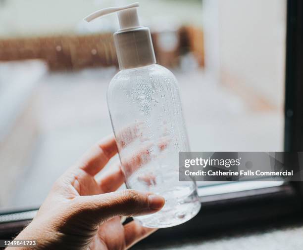hand holding a clear bottle of liquid soap - soap dispenser stock pictures, royalty-free photos & images