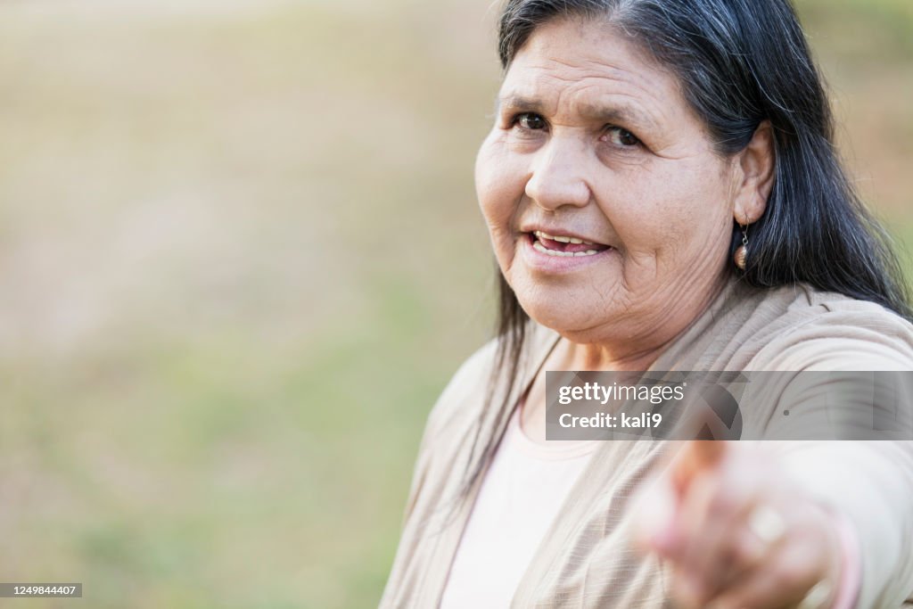 Senior Hispanic woman pointing at camera