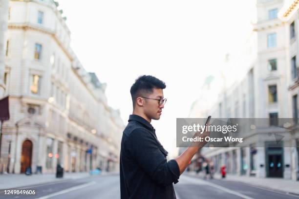 confident man exploring the city with smartphone - walking side by side stockfoto's en -beelden