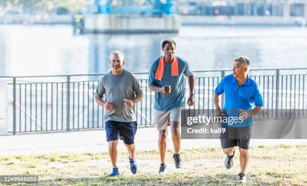 drei multiethnische männer joggen zusammen - 3 old men jogging stock-fotos und bilder