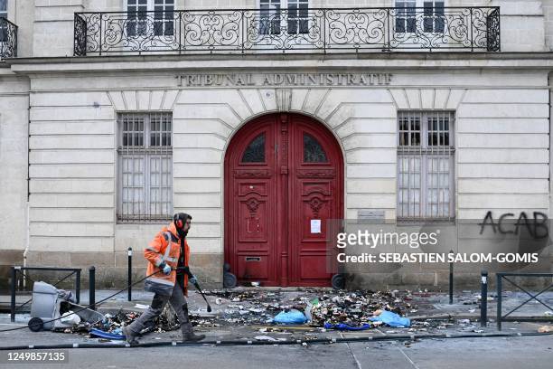 Woker cleans in front of the administrative court, littered with garbage and bearing an "ACAB" graffiti on the facade, the day after a demonstration,...