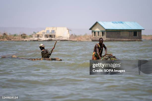 Two fishermen walking with their nets inside lake Turkana. The village of Kalokol has been flooded in the last few years due to climate change. The...