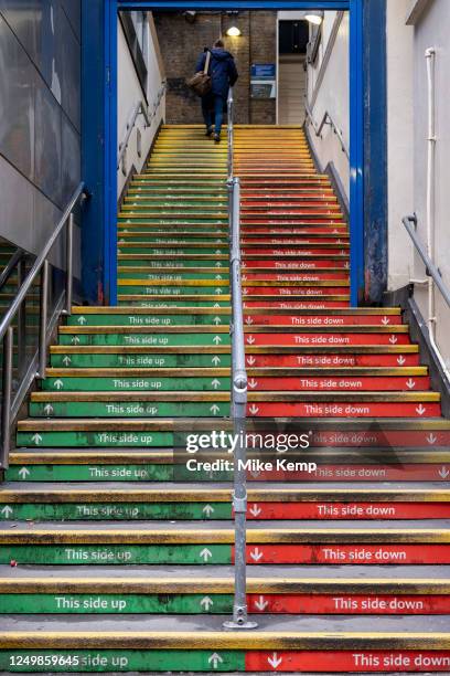 People taking the steps up to Charing Cross station in red and green read 'This side up' and 'This side down' on 26th March 2023 in London, United...