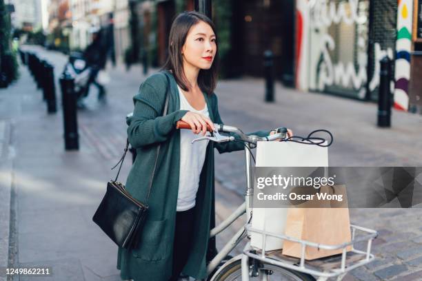 young woman exploring the city with a bike - buying a bike bildbanksfoton och bilder