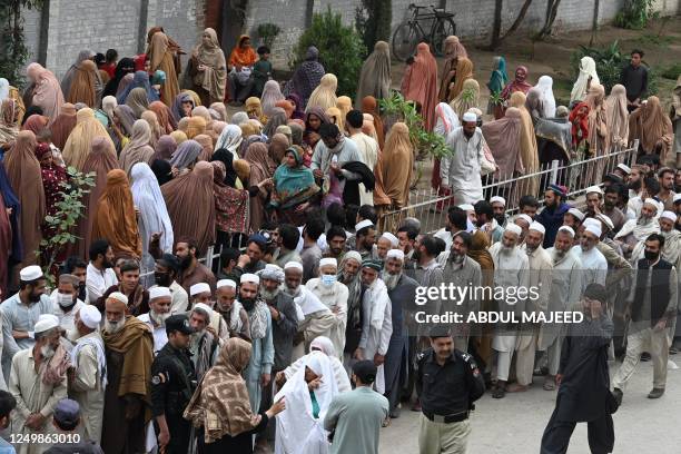 People wait to collect free bags of flour at a government distribution point in Peshawar on March 29 following an announcement by Pakistans Prime...