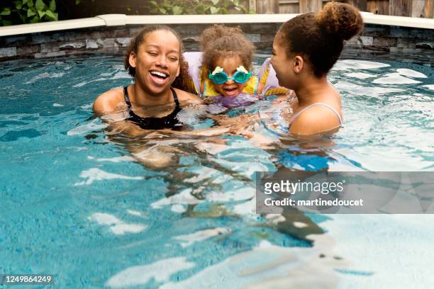 mixed-race-schwestern mit spaß im hinterhof-pool. - family playing in backyard pool stock-fotos und bilder