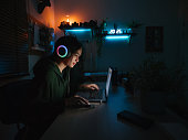 Young girl playing computer game on laptop at night