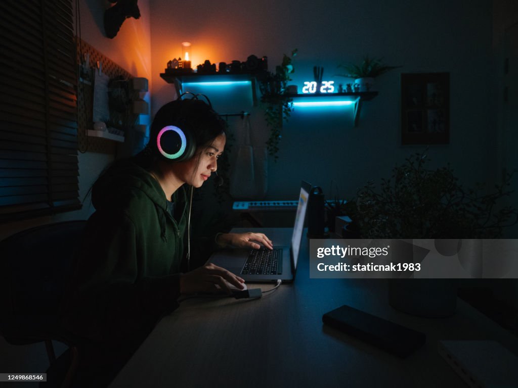 Young girl playing computer game on laptop at night