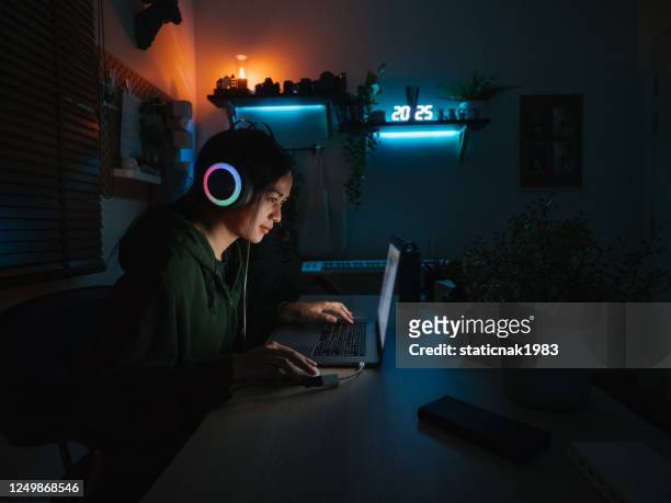 young girl playing computer game on laptop at night - arts culture and entertainment stock pictures, royalty-free photos & images