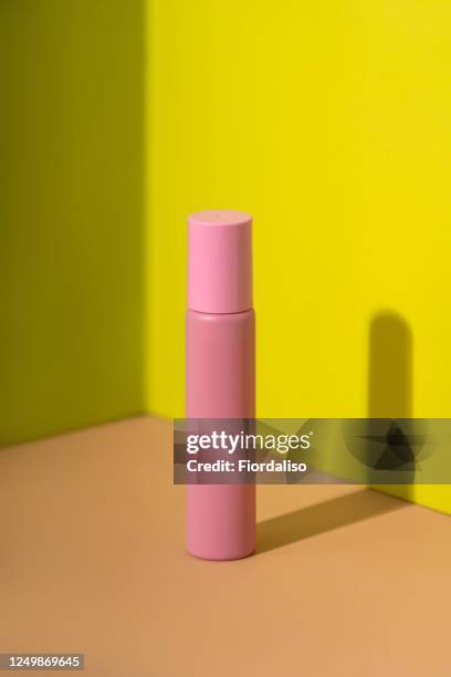 pink perfume bottle on a yellow-lemon and beige peach background - spray bottle stock-fotos und bilder