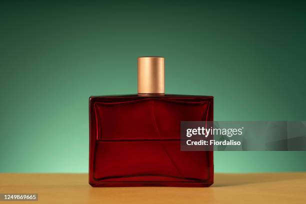 red glossy bottle with a liquid inside and a golden lid - aftershave bottle stock-fotos und bilder