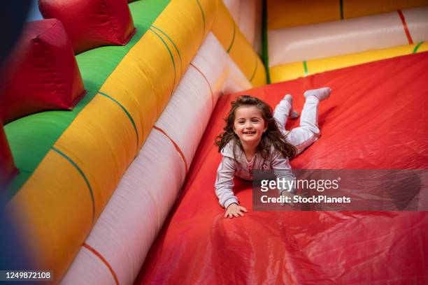 sweet little girl playing in a bouncy castle - trampoline jump stock pictures, royalty-free photos & images