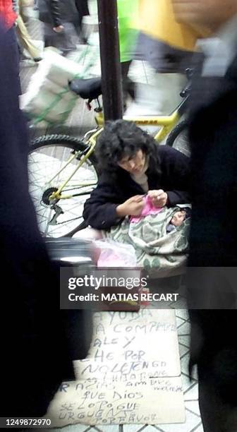 Woman begs with her son on a central Santiago street, Chile, while a group of businessmen passes next to her, 11 July 2001. Una mujer con su hijo...