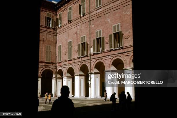 People are reflected in a mirror on a wall of the ticket office at the Palazzo Reale in Turin on March 29, 2023.