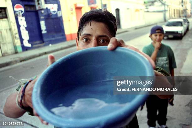 Street child takes a bucket of water to drink 23 July in Guatemala City. Un nino de la calle recibe un recipiente con agua para beber en Ciudad de...