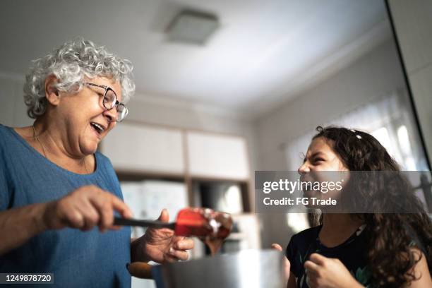 grandmother making chocolate with granddaughter at home - hispanic grandmother stock pictures, royalty-free photos & images