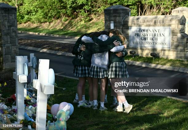 Girls embrace in front of a makeshift memorial for victims by the Covenant School building at the Covenant Presbyterian Church following a shooting,...