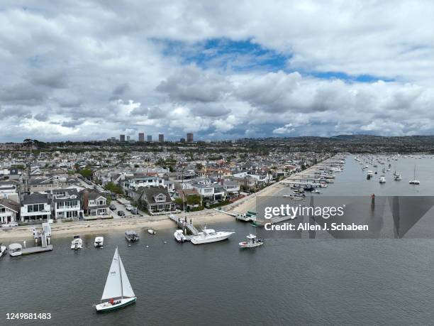 Newport Beach, CA A sailboat cruises past Balboa Island in Newport Beach Thursday, March 23, 2023.. Residents are mobilizing against fractional home...