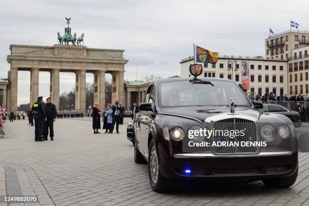 Britain's King Charles III and Britain's Camilla, Queen Consort sit in a state limousine after a welcome ceremony at Brandenburg Gate in Berlin, on...