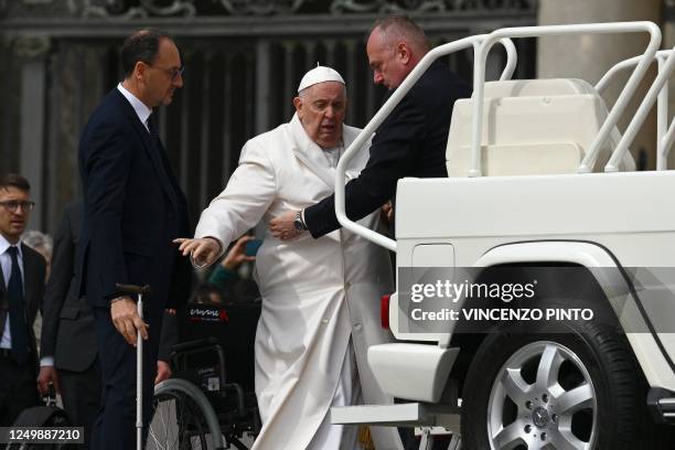 Pope Francis is helped get up the popemobile car as he leaves on March 29, 2023 at the end of the weekly general audience at St. Peter's square in...