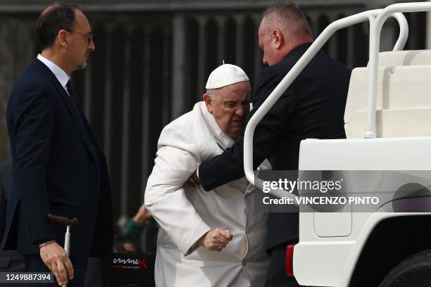 Pope Francis is helped get up the popemobile car as he leaves on March 29, 2023 at the end of the weekly general audience at St. Peter's square in...