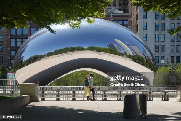 Visitors walk past the Cloud Gate sculpture in Millennium Park on June 15, 2020 in Chicago, Illinois. The park, which had been closed to visitors to...