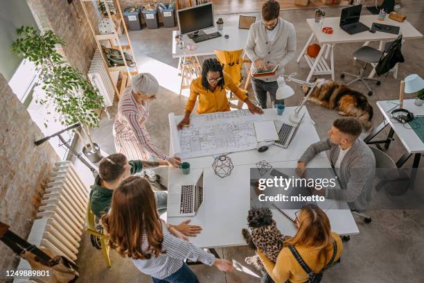 multi-ethnic group discussing an architectural layout - new business construction stock pictures, royalty-free photos & images