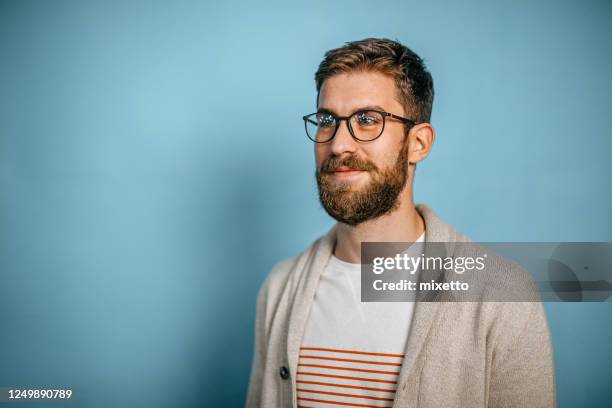 studio skott av en ung man tittar i sidled - blue background portrait bildbanksfoton och bilder