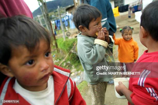 Varios niños toman el desayuno acompañados por sus madres fuera de sus casa en el sector popular de Tucucho al noreste de Quito, el 11 de julio de...