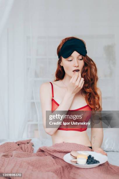 young beautiful woman eating in bed - augenmaske stock-fotos und bilder