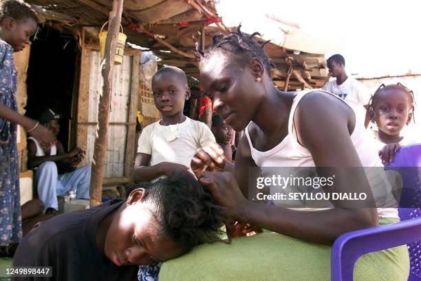 Une Senegalaise tresse des cheveux dans la cour de leur maison, le 30 Aout 2002 à Captage, bidonville de Dakar. Ici comme dans pres d'une vingtaine...