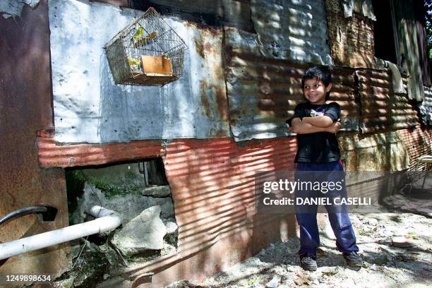 Uruguayan slum....A boy who lives in a slum of the periphery of Montevideo, shows his two birds in the backyard of his house, 17 October 2002. The...