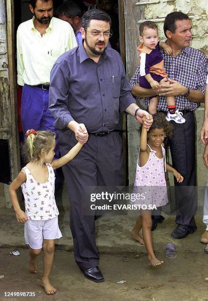 Economy Minister Antonio Palocci takes two of local children in Teresina, northern Brazil, by the hand 10 January, 2003. Palocci and President Luiz...