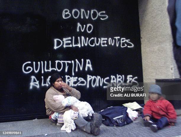 Woman an her children begg outside of Banco Rio, in the financial district of Buenos Aires, 18 June 2002. AFP PHOTO/Ali BURAFI Una mujer con sus dos...
