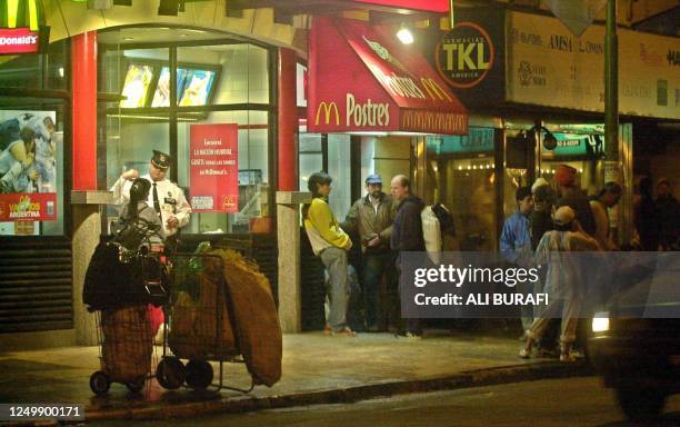 Several garbage collectors wait outside of a fast food chain in Buenos Aires, 24 June 2002. AFP PHOTO/Ali BURAFI Varios recicladores de basura, entre...